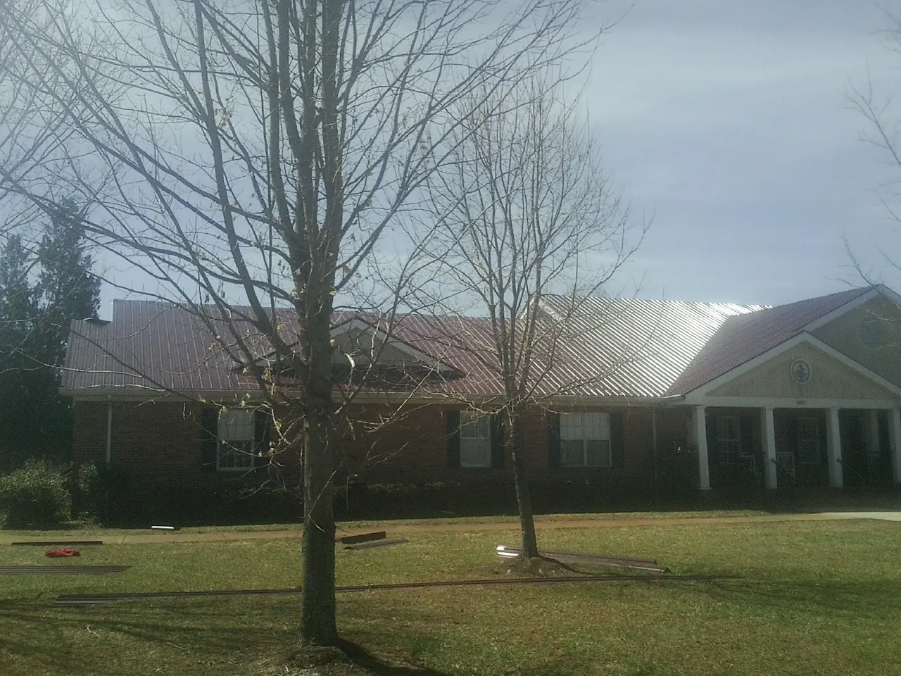 Red metal roof on a brick building seen from the front lawn in Cornwall