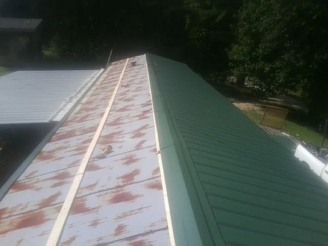 Old rusted panels beside newly installed green metal roofing — Wind Damage Roof Repair by Roofing Brothers in Cornwall